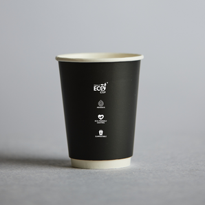 Black paper cup with a beige rim on a gray background