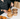 Person holding a piece of fried chicken with paper containers on a table